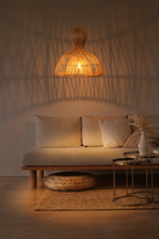 Aura rattan pendant light casting warm woven shadow patterns on a wall above a neutral linen daybed in an evening living room setting