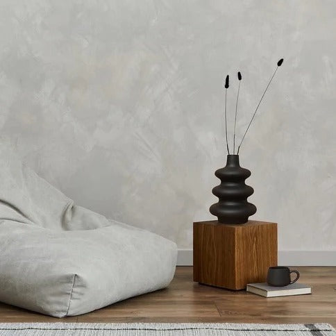 Black Mezo vase with dried stems on a wood block in a minimalist living room