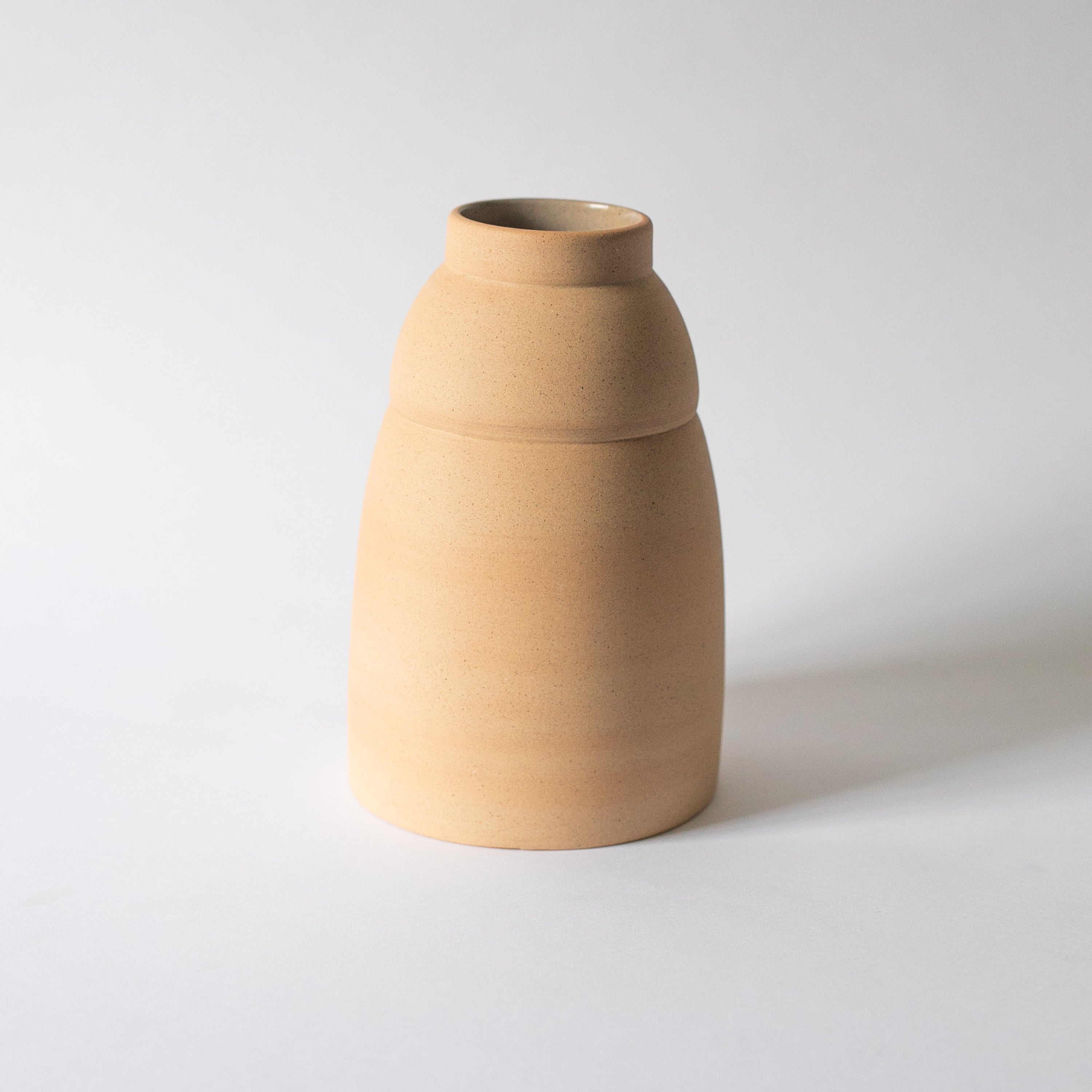 Chubby ceramic vase shown in profile showing its stepped shoulder and short neck
