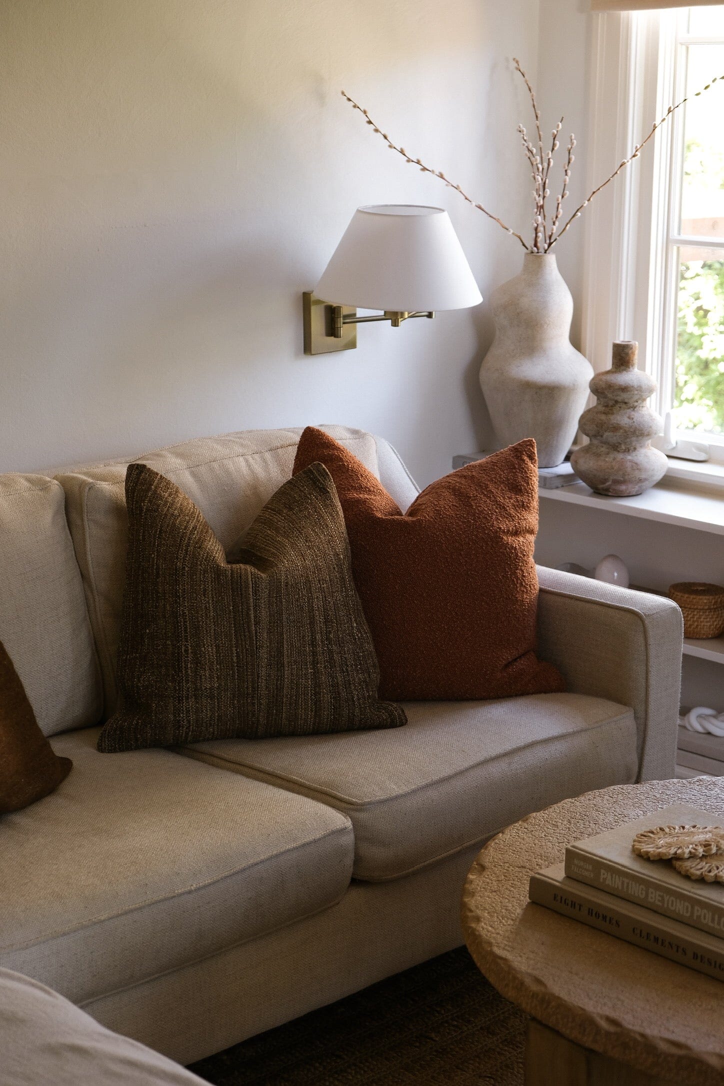 Cream terracotta vessel styled on a side table beside a linen sofa in a sunlit room