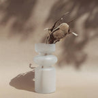 Iris frosted glass vase with stacked ribbed form holding a dried protea stem