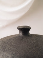 Close view of the Rovi vessel showing its dark textured terracotta surface and short neck