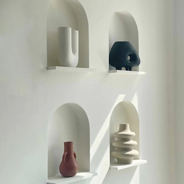 Sculptural tiered vases styled in white arched wall niches