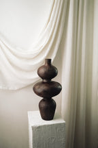 Side profile of the Sewu terracotta vessel against soft white drapery