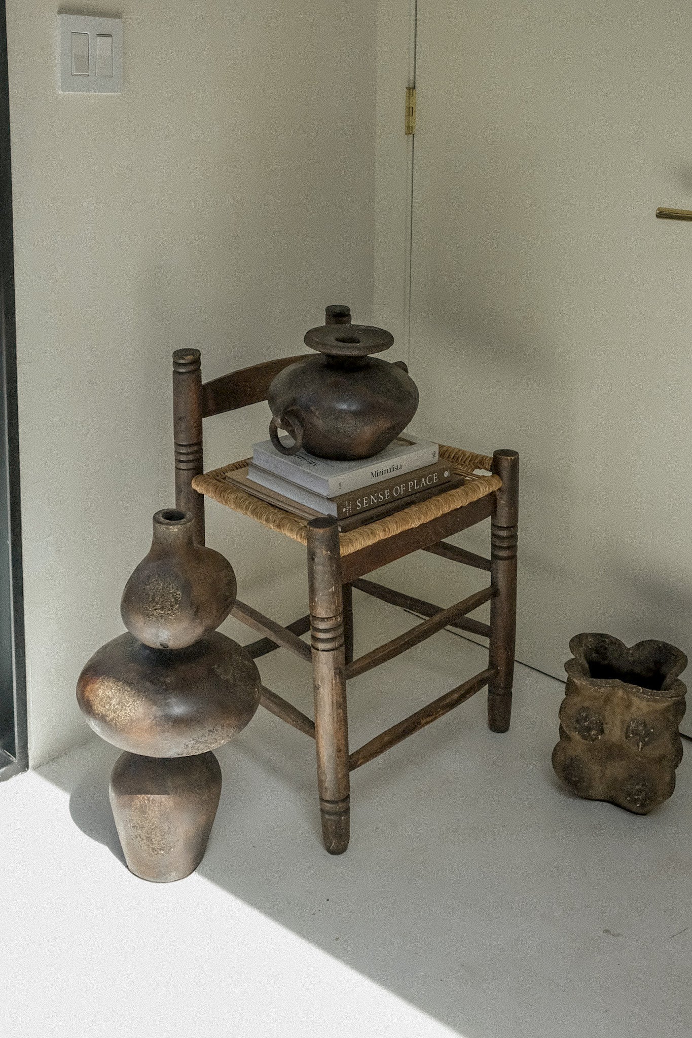 Sewu vessel styled beside a woven rush chair in a minimalist plaster room