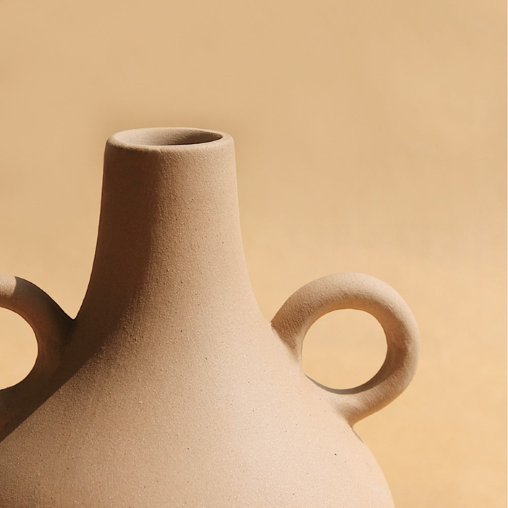 Soft cream Harappan vase showing its rounded form and slim neck