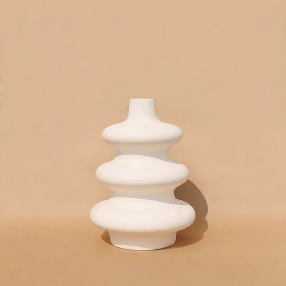 Soft white Mezo ceramic vase with tiered sculptural form on a tan backdrop