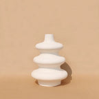 Soft white Mezo ceramic vase with tiered sculptural form on a tan backdrop