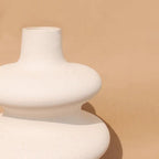  Soft white Mezo ceramic vase with tiered sculptural form on a tan backdrop