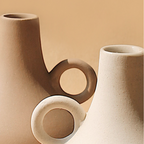 Two tan Harappan ceramic vases with ring handles in a sculptural grouping