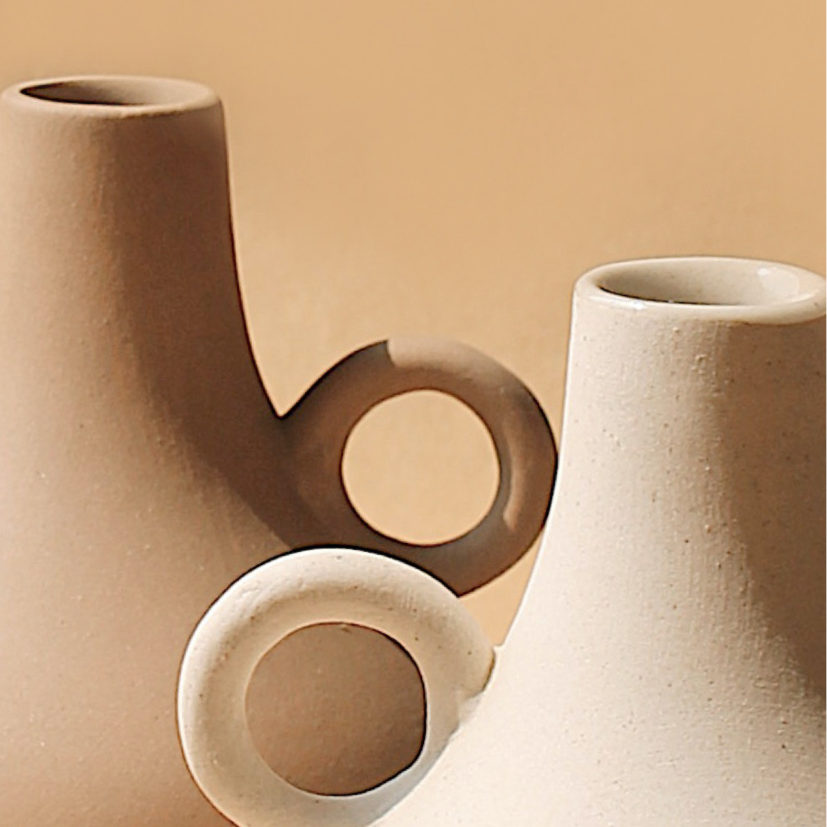 Two tan Harappan ceramic vases with ring handles in a sculptural grouping