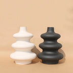 White and black Mezo tiered vases grouped on a tan background