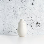 White matte stoneware bud vase against a speckled gray background