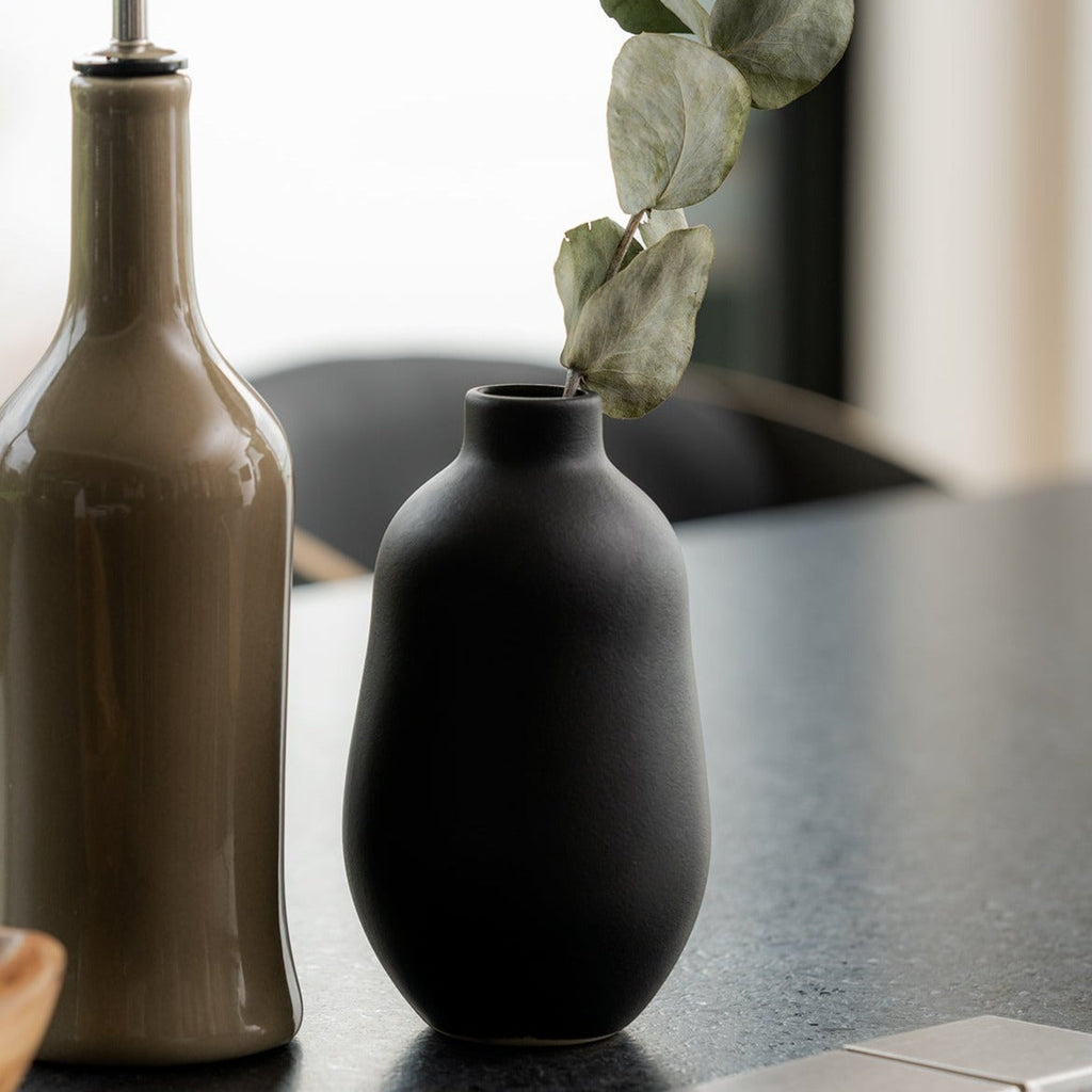 black stoneware bud vases grouped with a eucalyptus stem