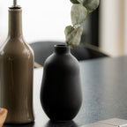 black stoneware bud vases grouped with a eucalyptus stem